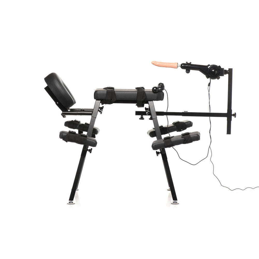 Black obedience bench with adjustable restraints and a sex machine with a dildo.
