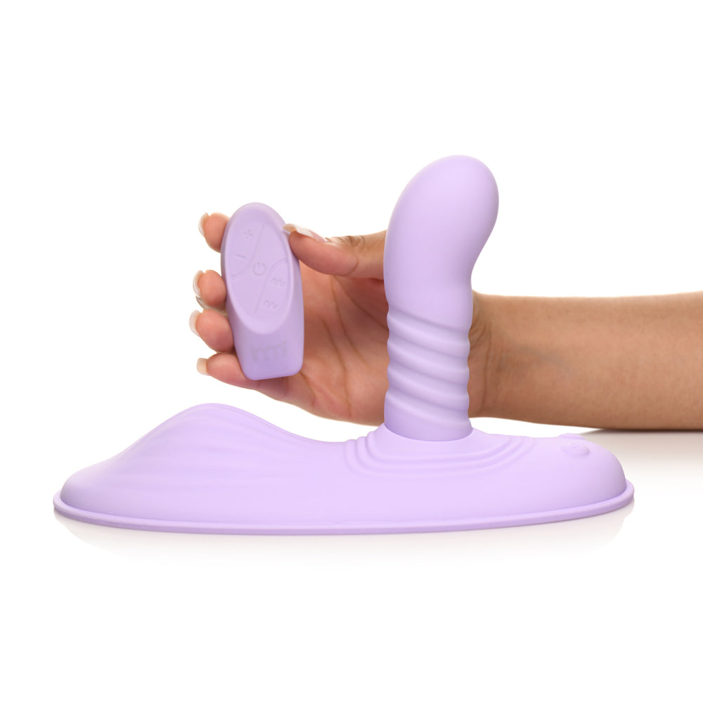 A purple silicone grinding pad with a ribbed stimulator and remote control.