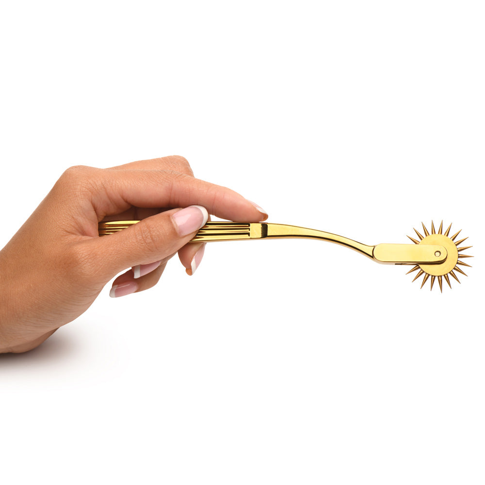 A gold stainless steel Wartenberg sensation wheel held by a hand.
