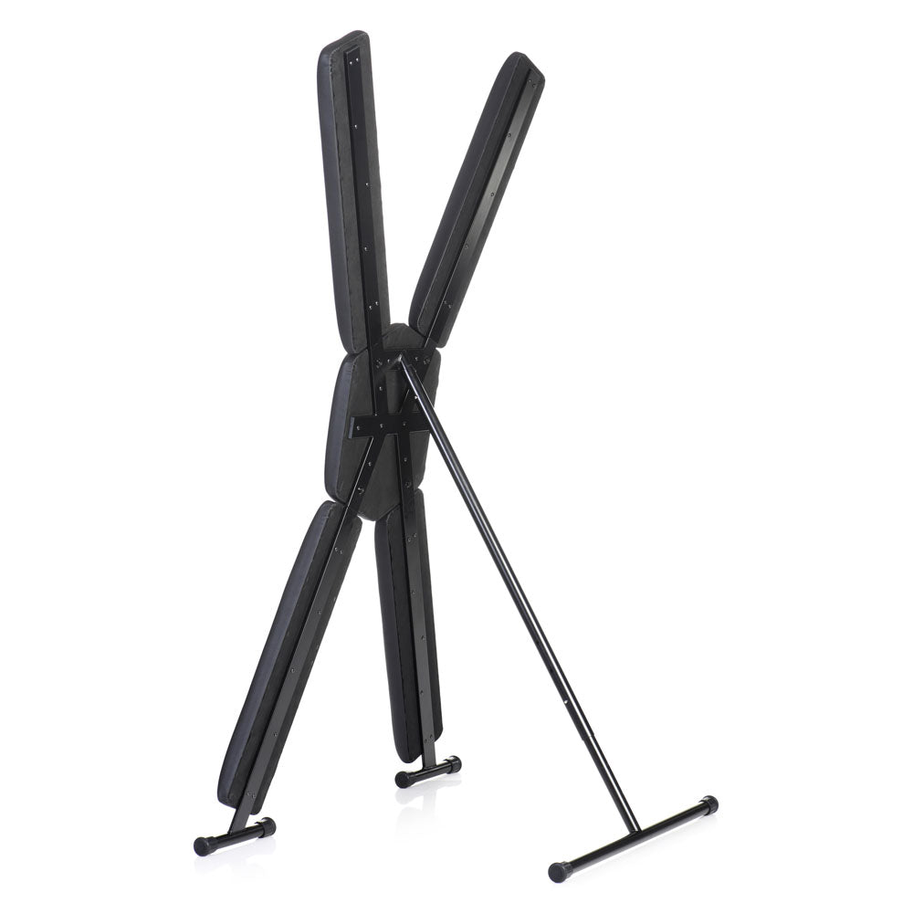 A black free-standing St. Andrew's cross with padded restraints.