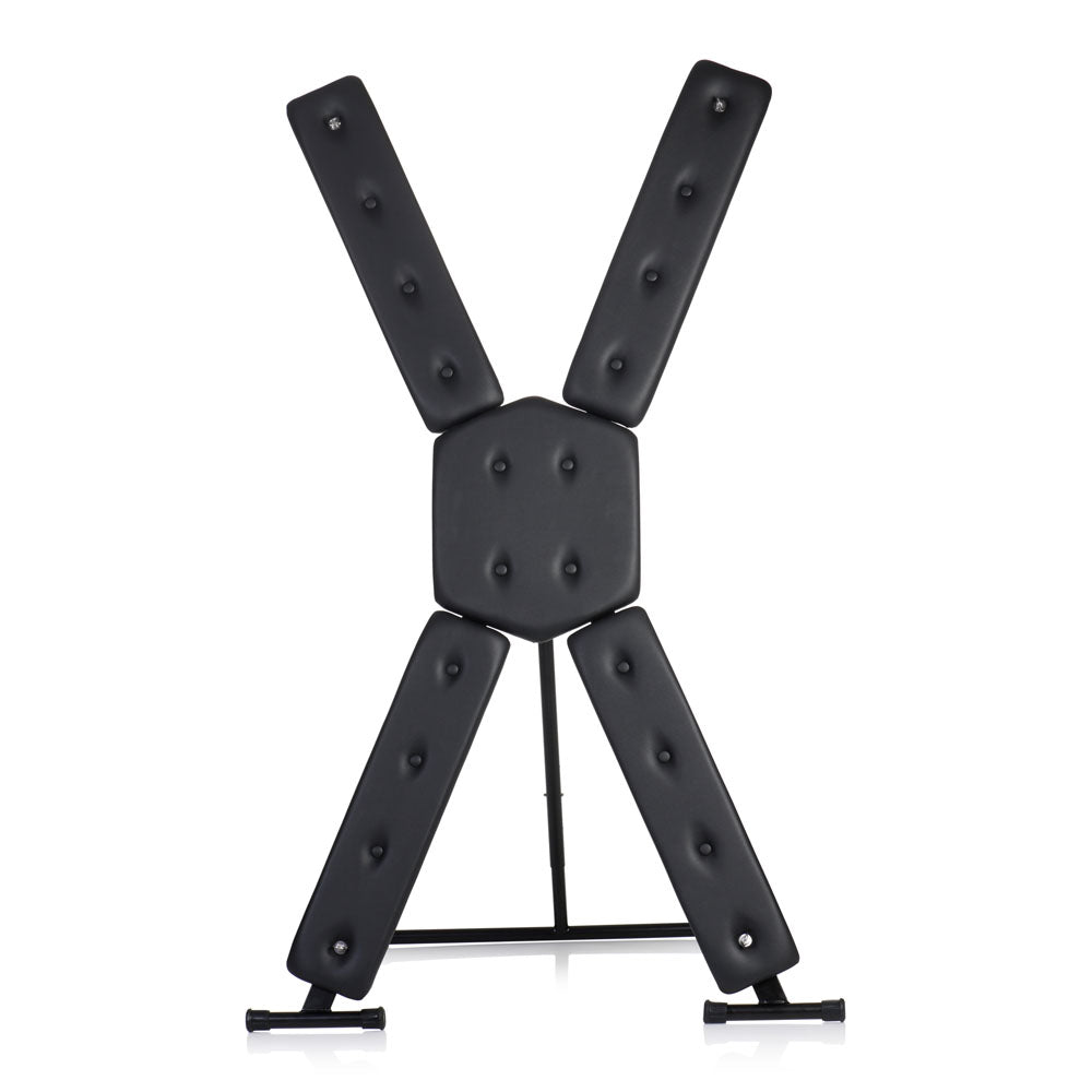 A black St. Andrew's cross with padded restraints and a metal stand.