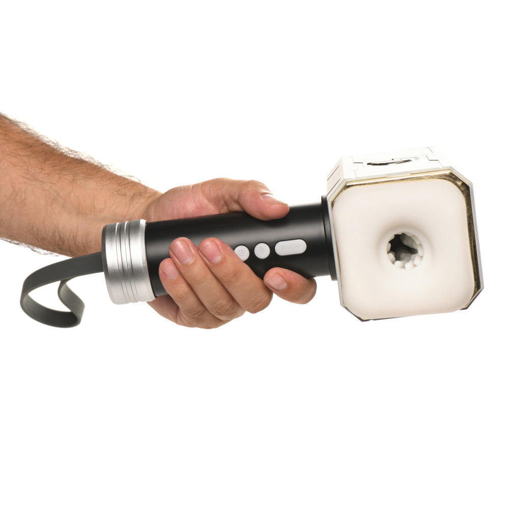 A hand holds a black and silver vibrating and sucking device with a white textured opening.