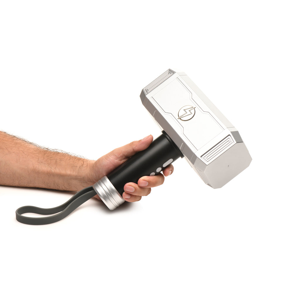 A hand holds a silver and black Thor hammer-shaped vibrator with a wrist strap.
