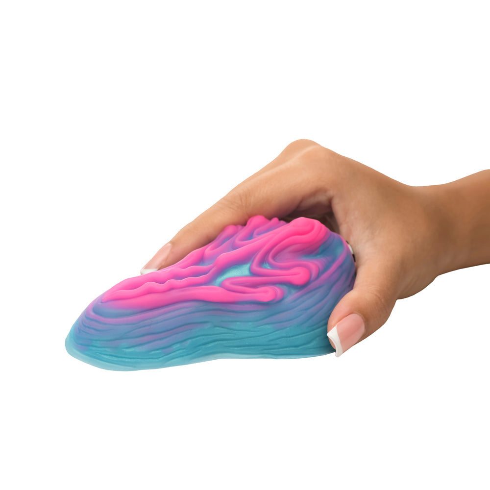A hand holds a pink and blue silicone grinder with a textured surface.