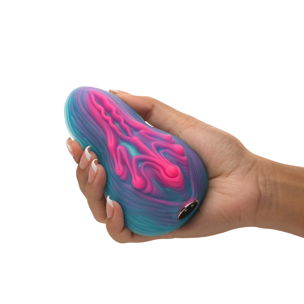 A hand holds a blue and pink silicone vibrator with a textured surface.