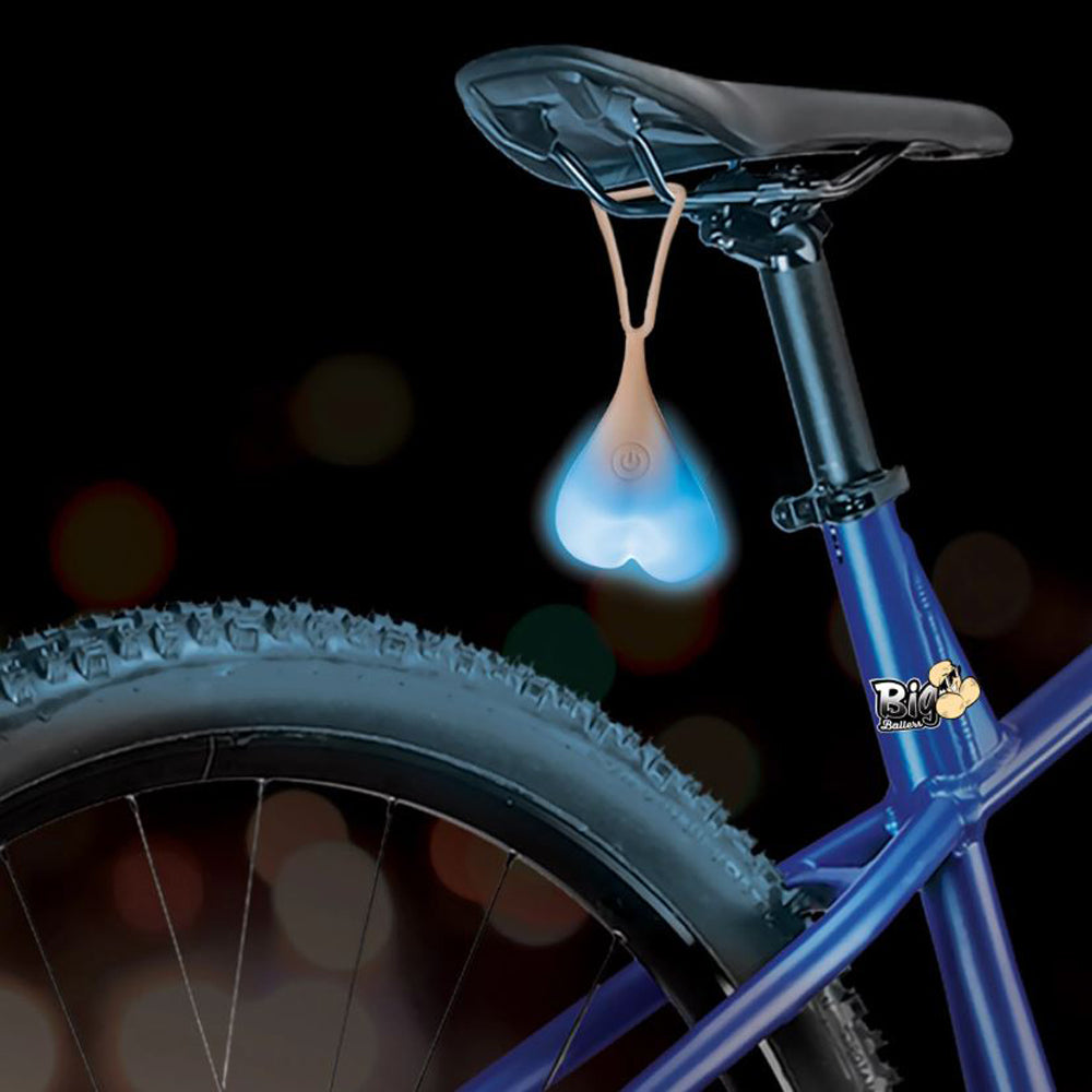 Blue silicone truck nuts light hanging from a bicycle seat.