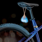 Blue silicone truck nuts light hanging from a bicycle seat.