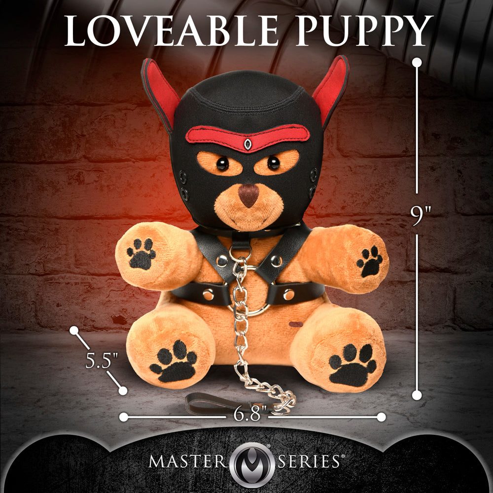 A 9-inch plush teddy bear wearing a black neoprene hood with red accents, a black harness, and a chain leash.