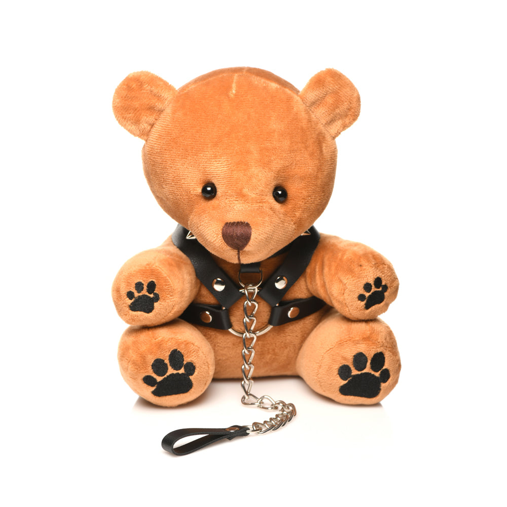 A brown teddy bear wearing a black spiked harness and chain leash.