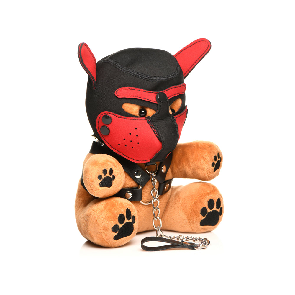 A plush teddy bear wearing a black and red pup hood and harness with a chain leash.