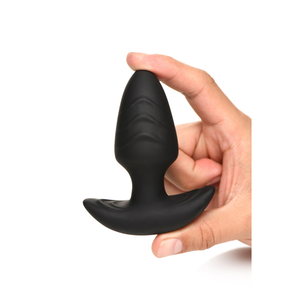 A black silicone anal plug with a textured tip and flared base is held by a hand.
