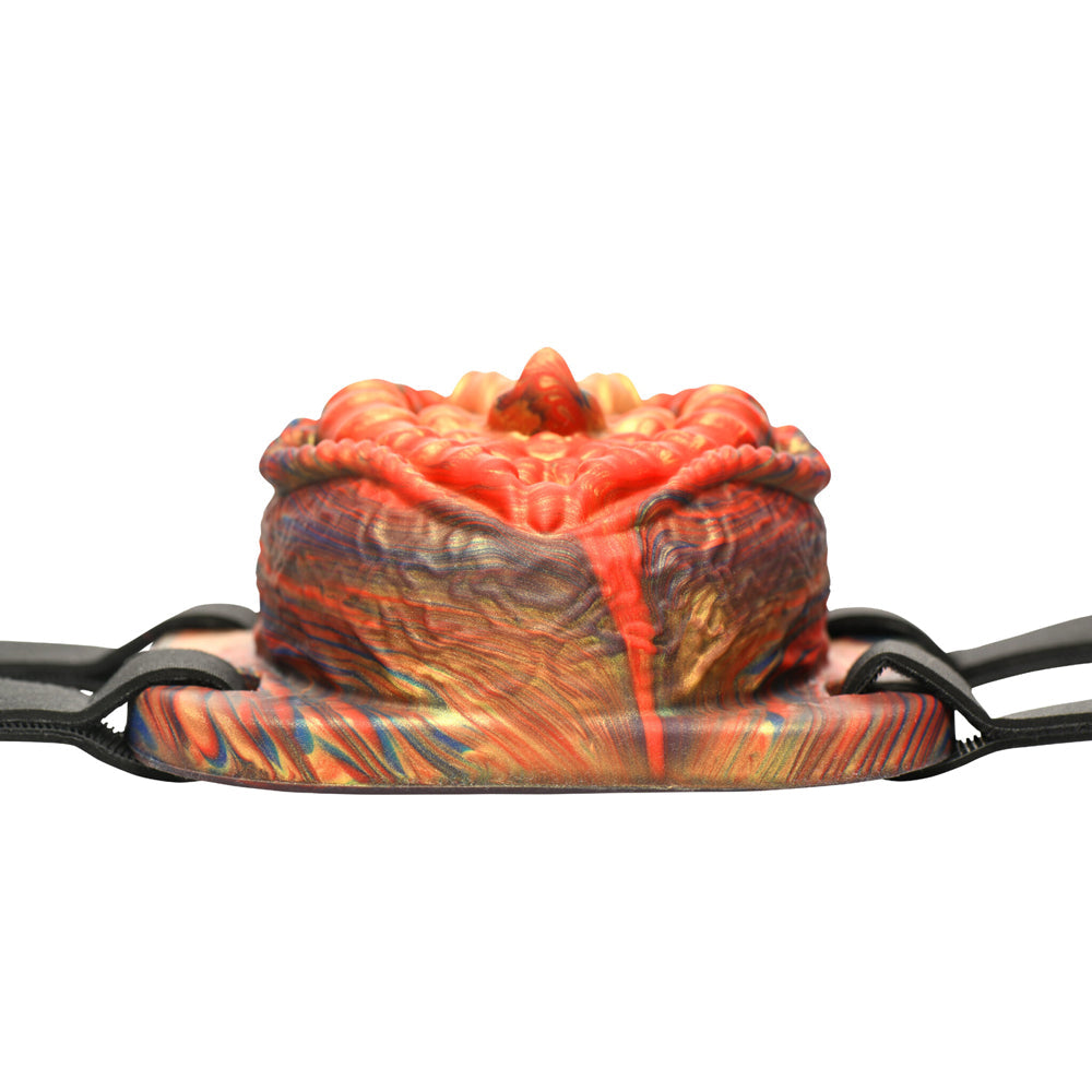 A vibrator with a textured, red and gold patterned surface and black straps.