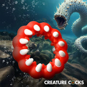 Red silicone cock ring with white fangs and textured bumps.