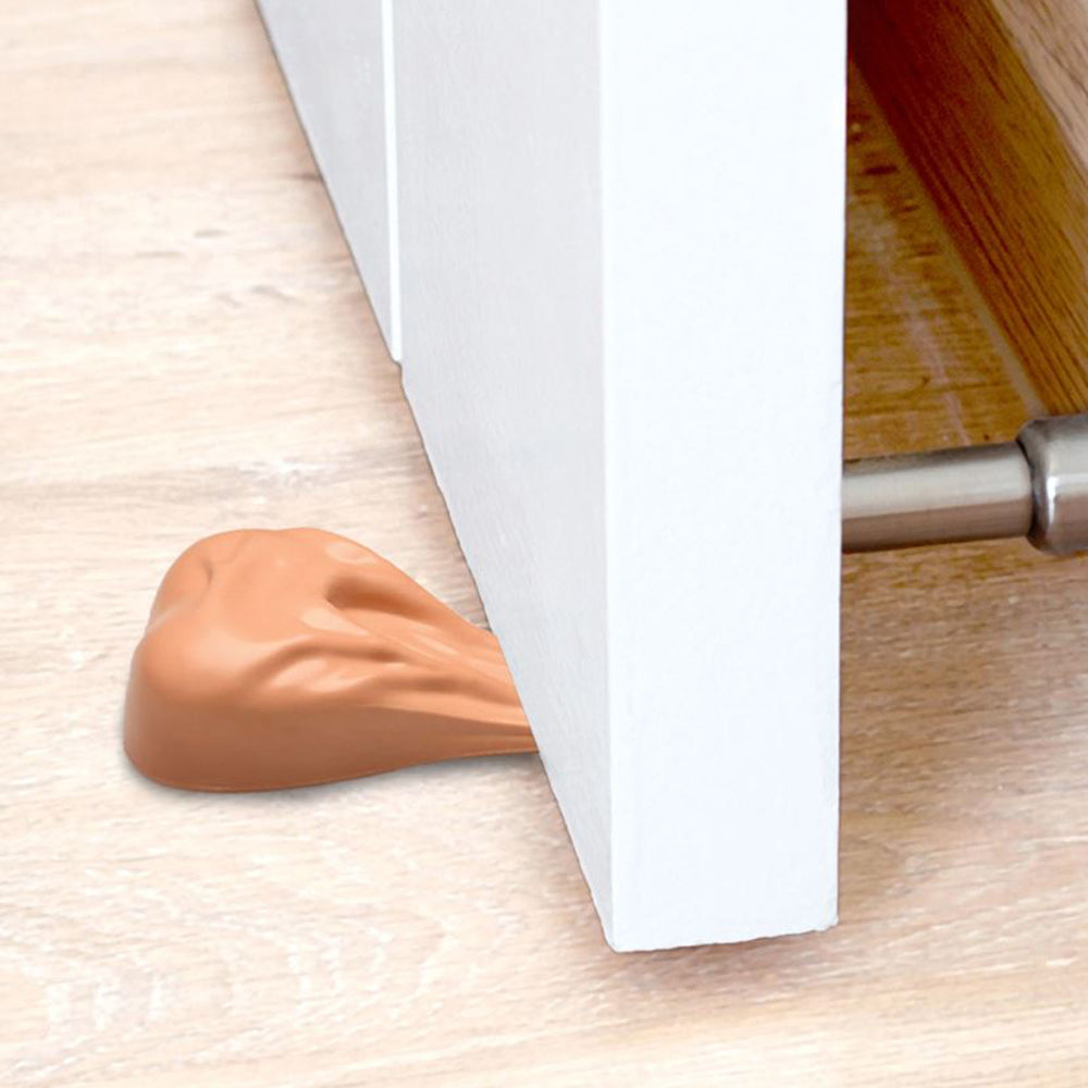 A tan silicone door stop shaped like a pair of large balls is wedged under a white door.