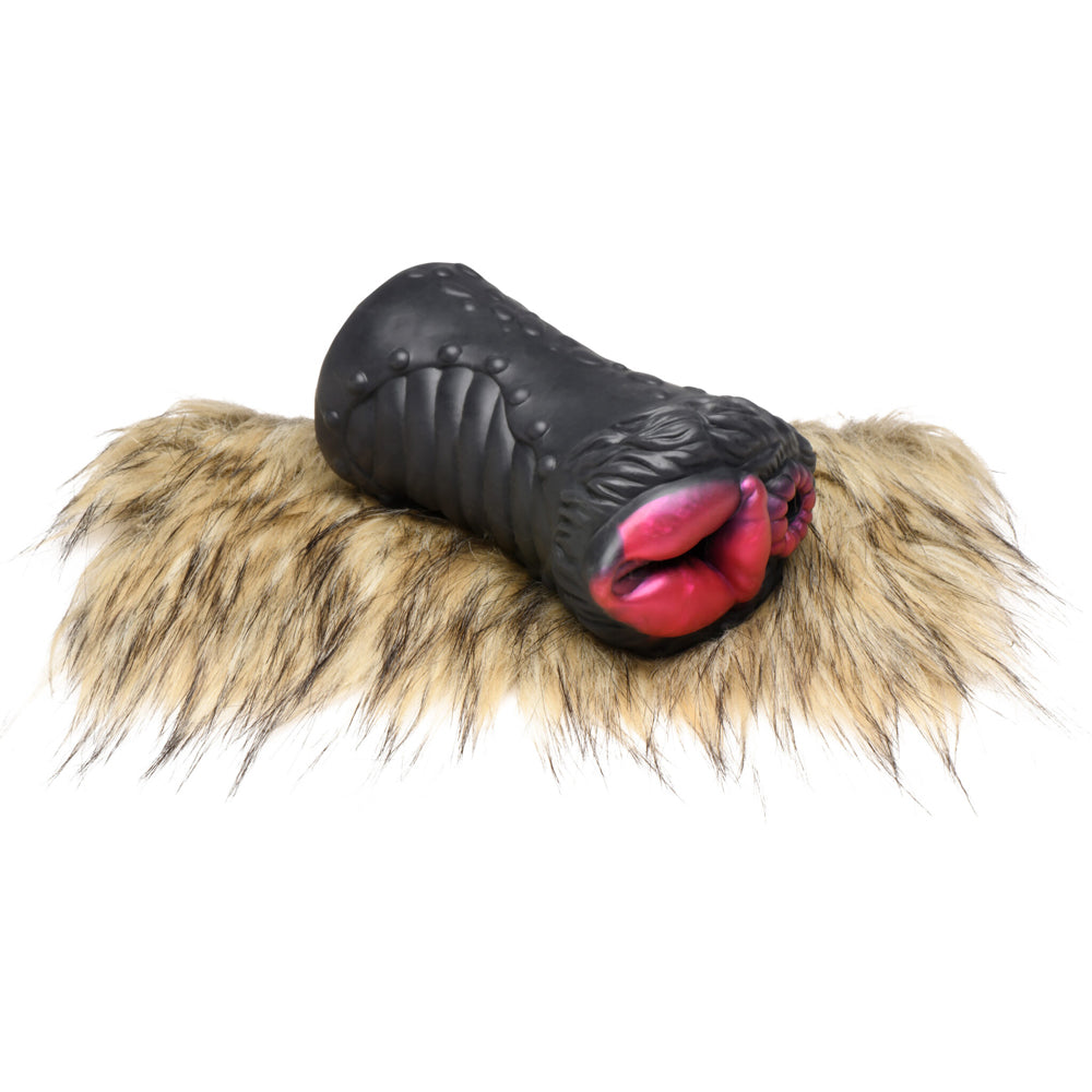 Black silicone stroker with pink lips on a furry mat.