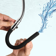 Silicone enema nozzle with a flexible metal hose spraying water.