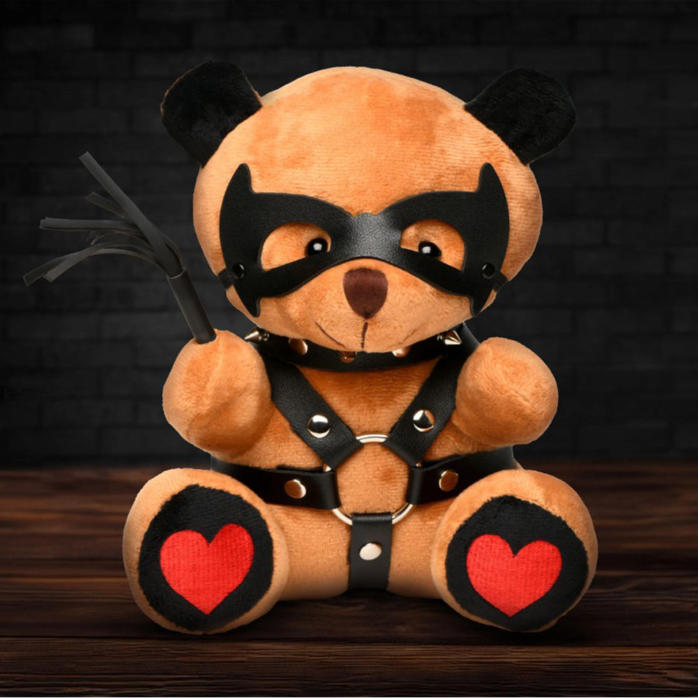 Brown teddy bear with black vegan leather mask, collar, harness, and whip, and red heart paw pads.