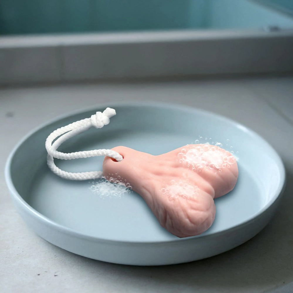 A pink, penis-shaped soap on a rope with bubbles in a blue dish.