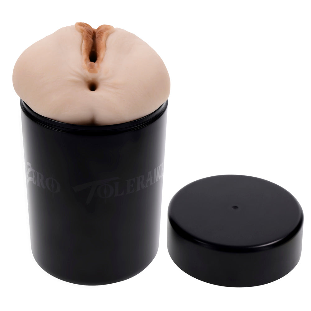 A flesh-toned dual entry stroker sits in a black canister with a lid beside it.