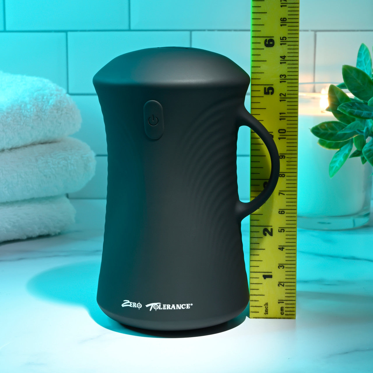 A black gyrating ball stroker with a handle and power button, next to a ruler.