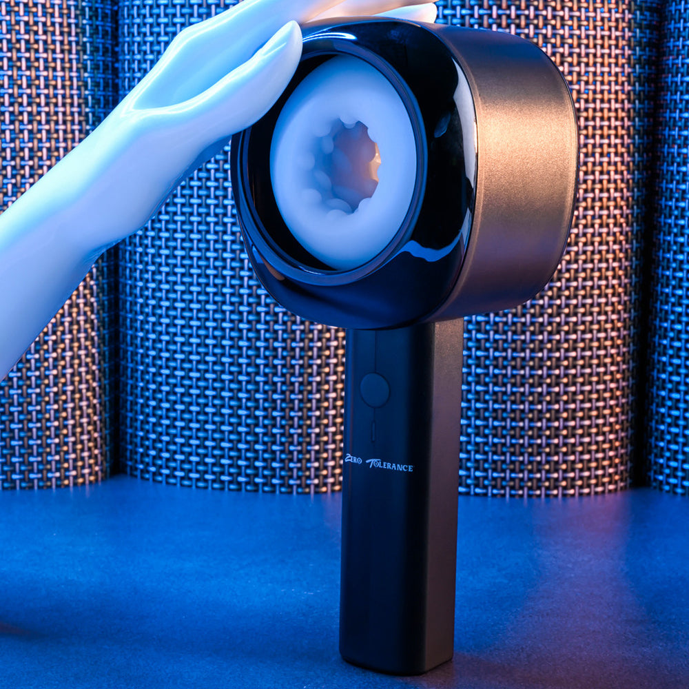 A hand touches a black rechargeable stroker with a textured white interior.