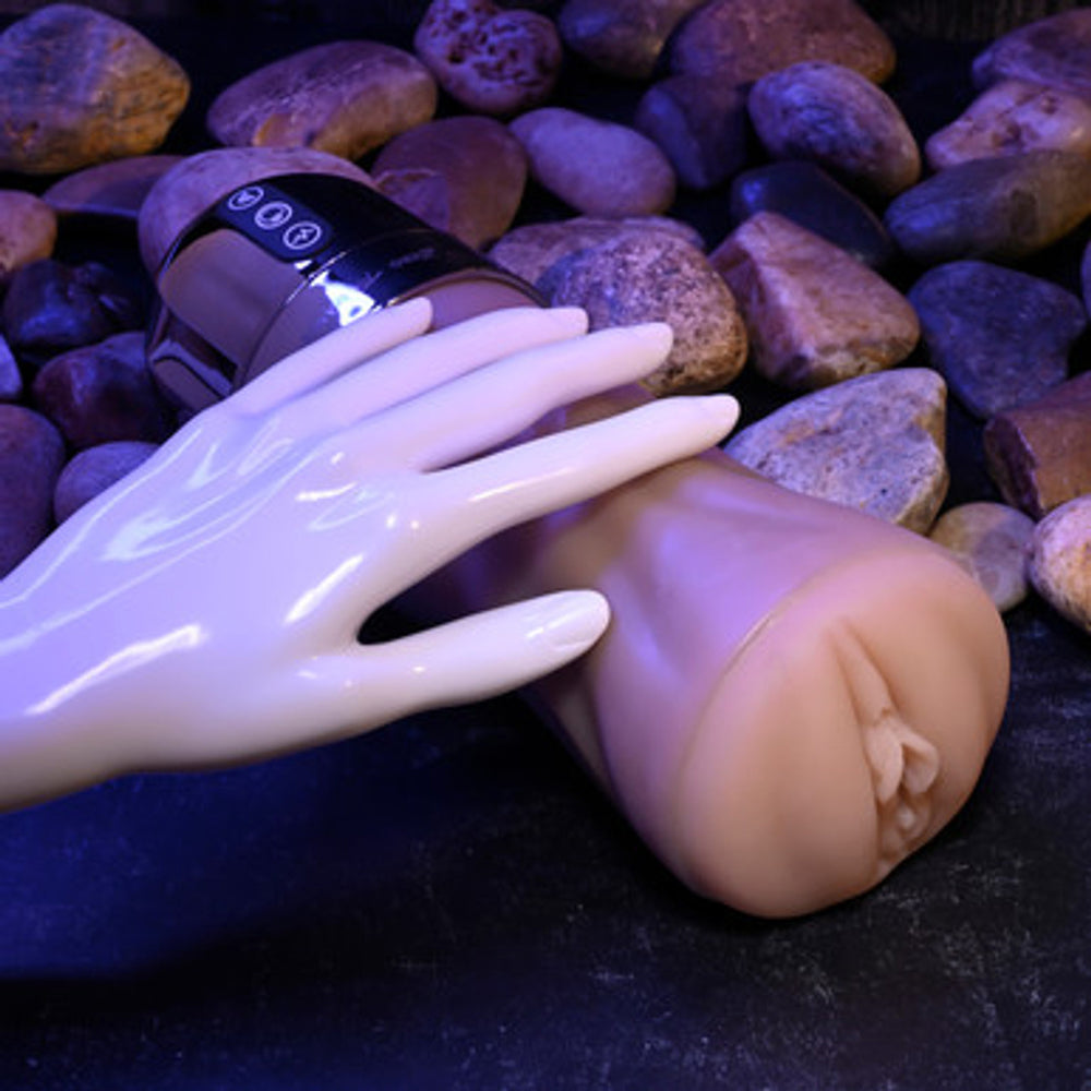 A vibrating stroker with a realistic texture and a hand holding it.