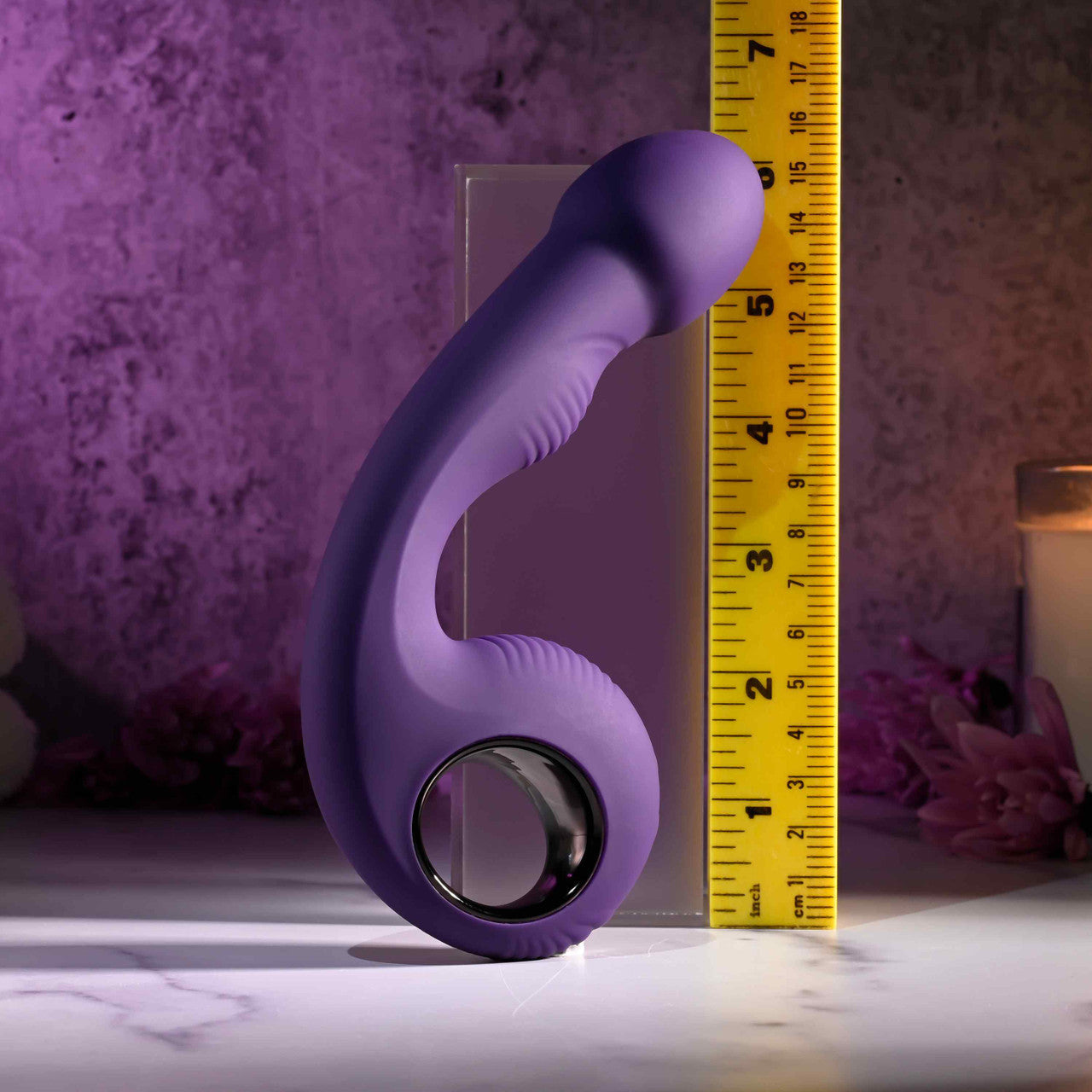 A purple silicone vibrator is measured against a ruler.