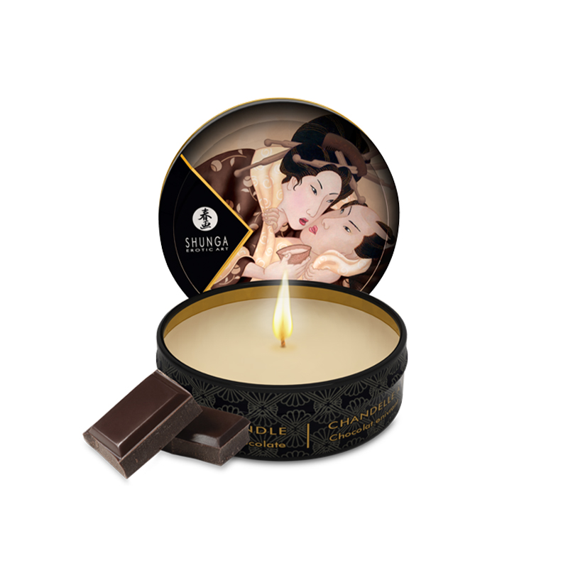 Shunga chocolate massage candle with a lit wick and two chocolate pieces.