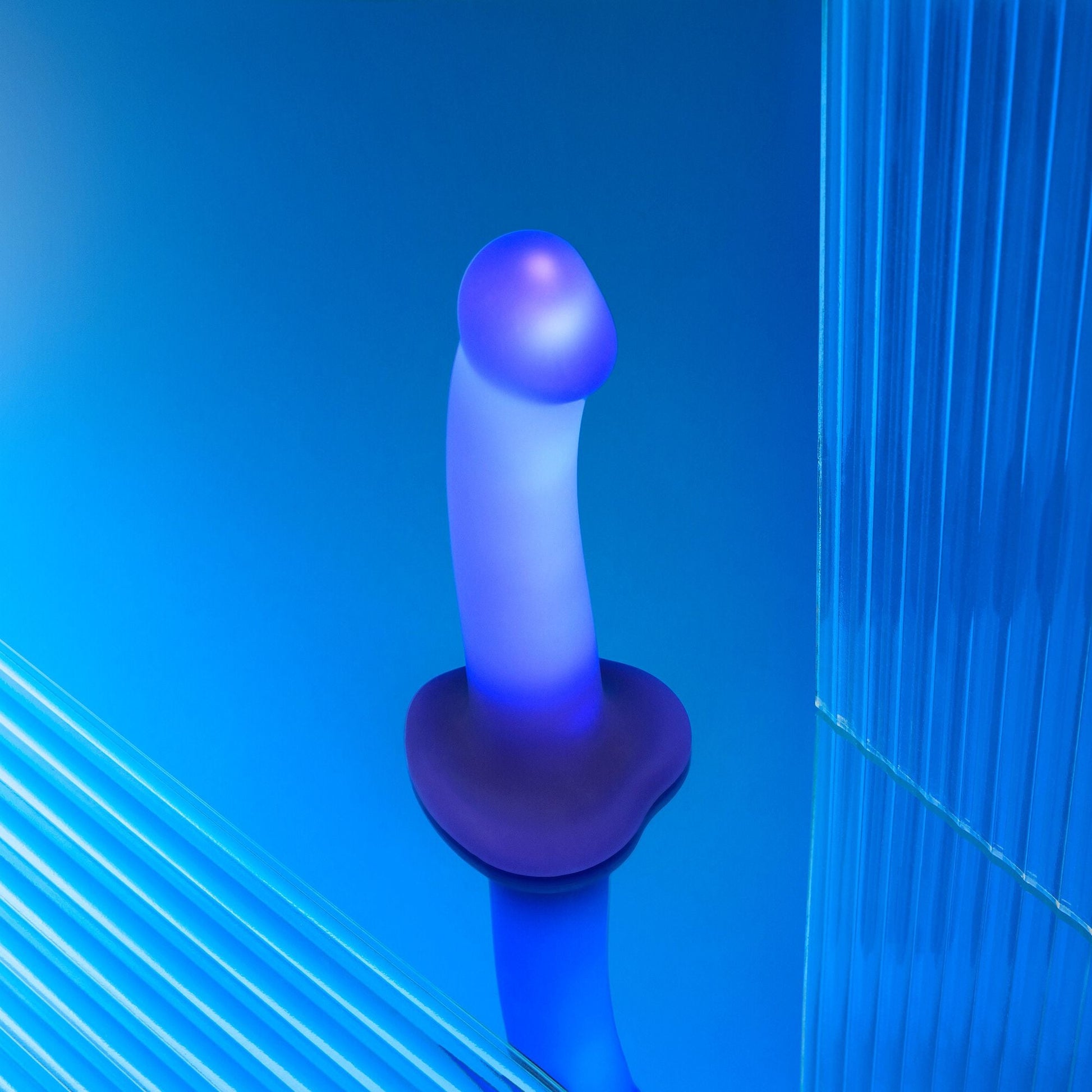 A purple silicone dildo with LED lights and a suction base on a blue background.