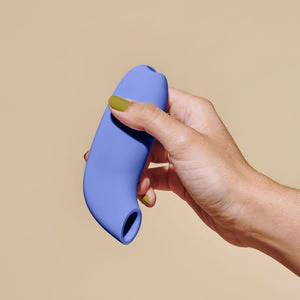 A purple silicone suction stimulator held in a hand.
