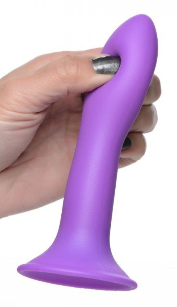 Purple silicone dildo with a suction cup base held by a hand.