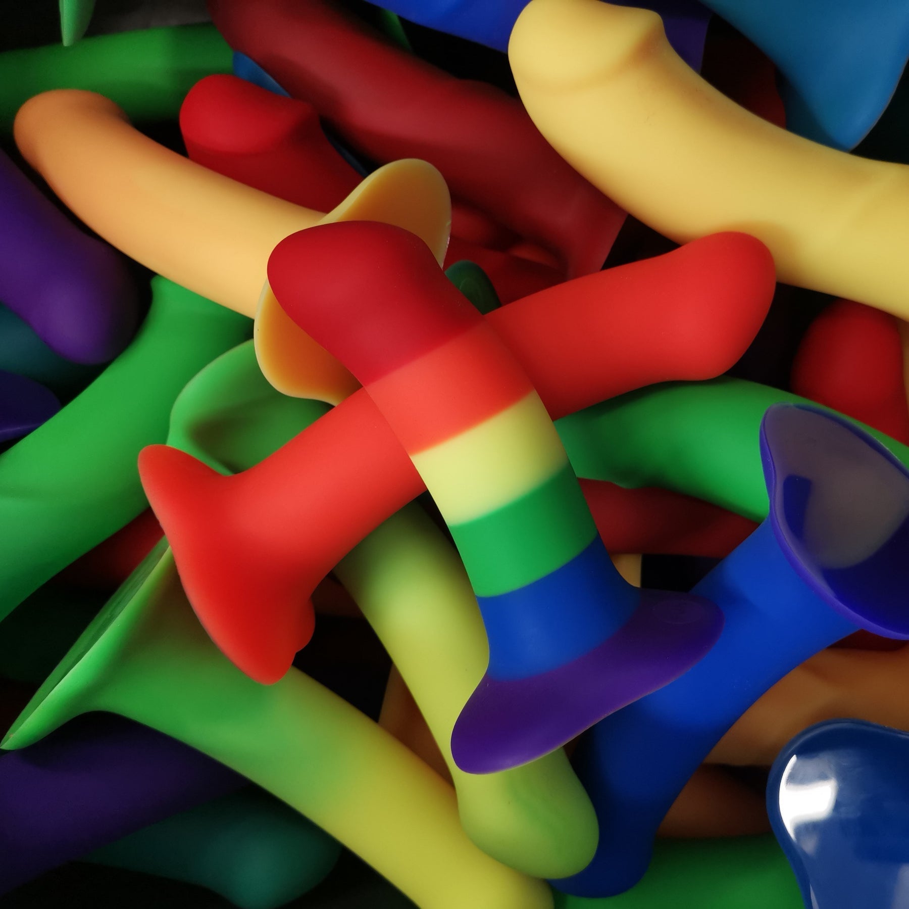 A pile of colorful dildos in various sizes and rainbow patterns.