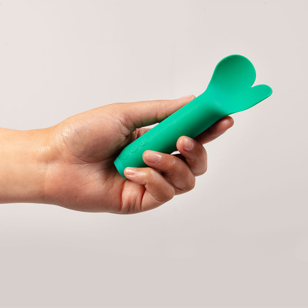 Emerald green silicone vibrator with a heart-shaped tip held in a hand.