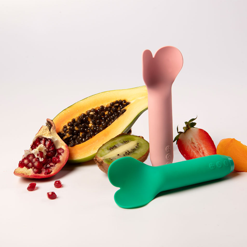 Emerald green heart-tip vibrator with fruits.