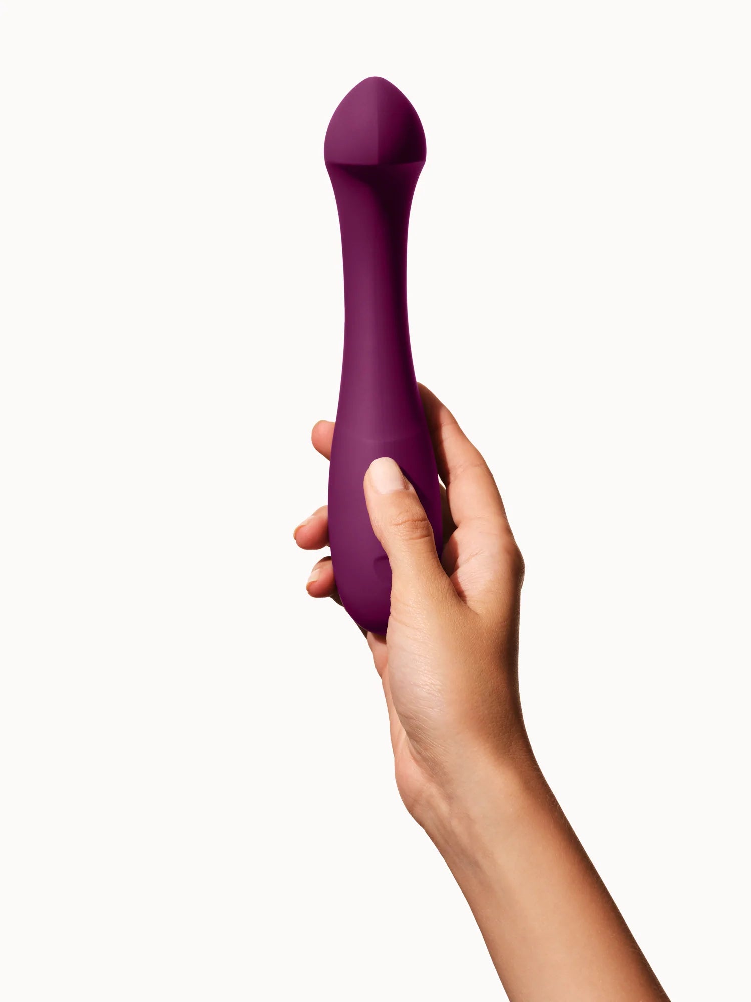 A plum-colored G-spot vibrator held in a hand.