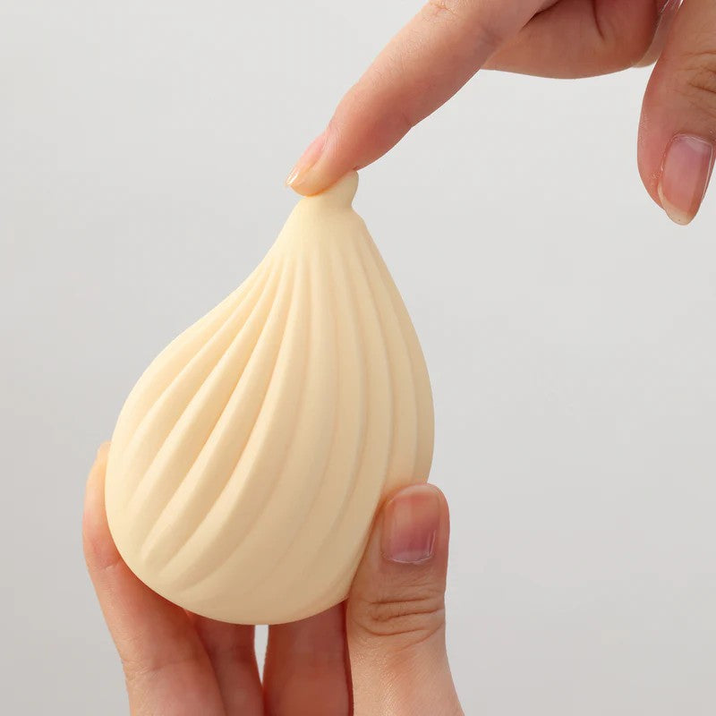 A ribbed, light yellow silicone massager is held by two hands.