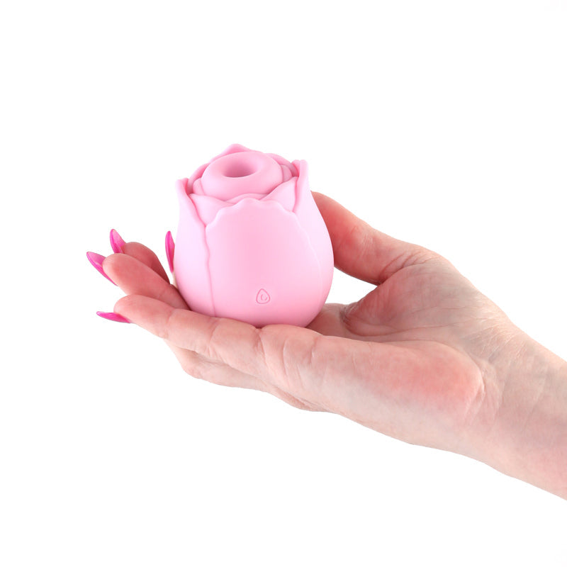 A pink rose-shaped silicone stimulator held in a hand.