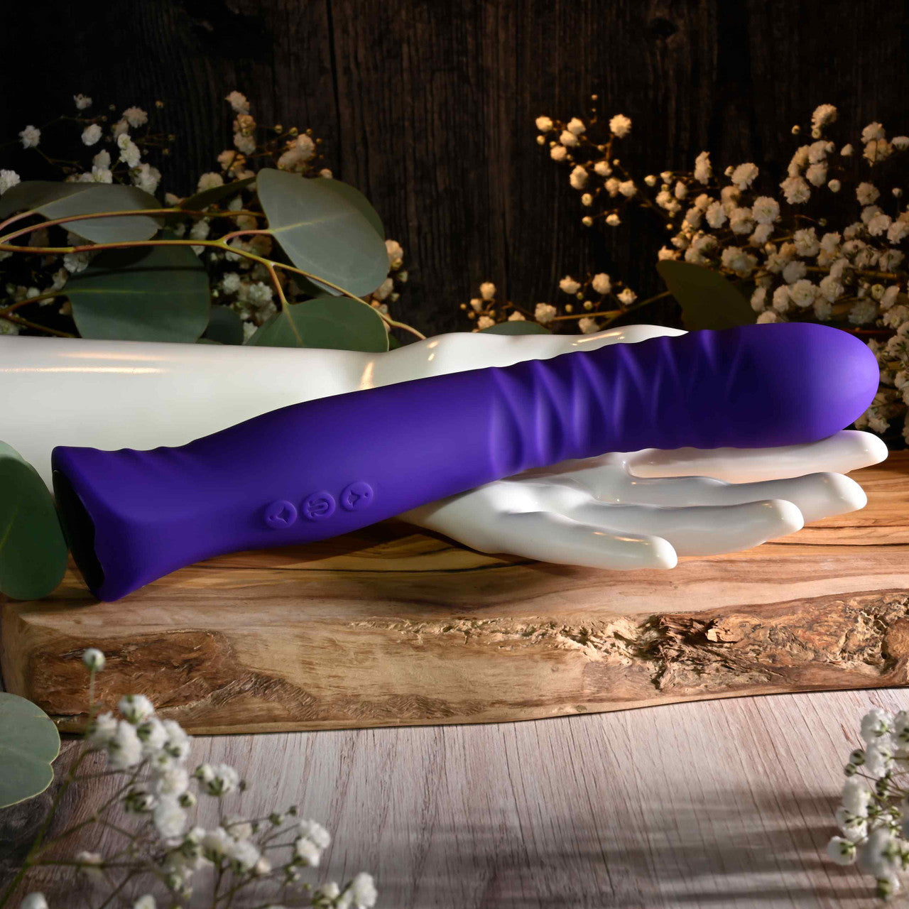Purple textured silicone vibrator on a white hand-shaped stand.