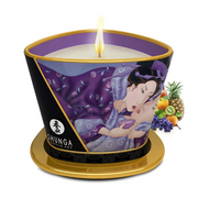 A Shunga massage candle with exotic fruit imagery and a lit wick.