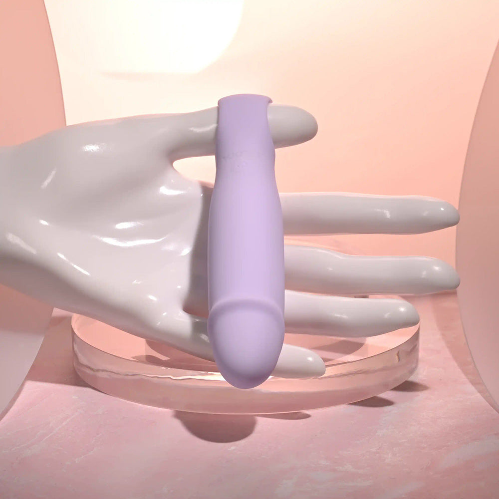 A lavender silicone vibrator with a tapered tip is held by a white mannequin hand.