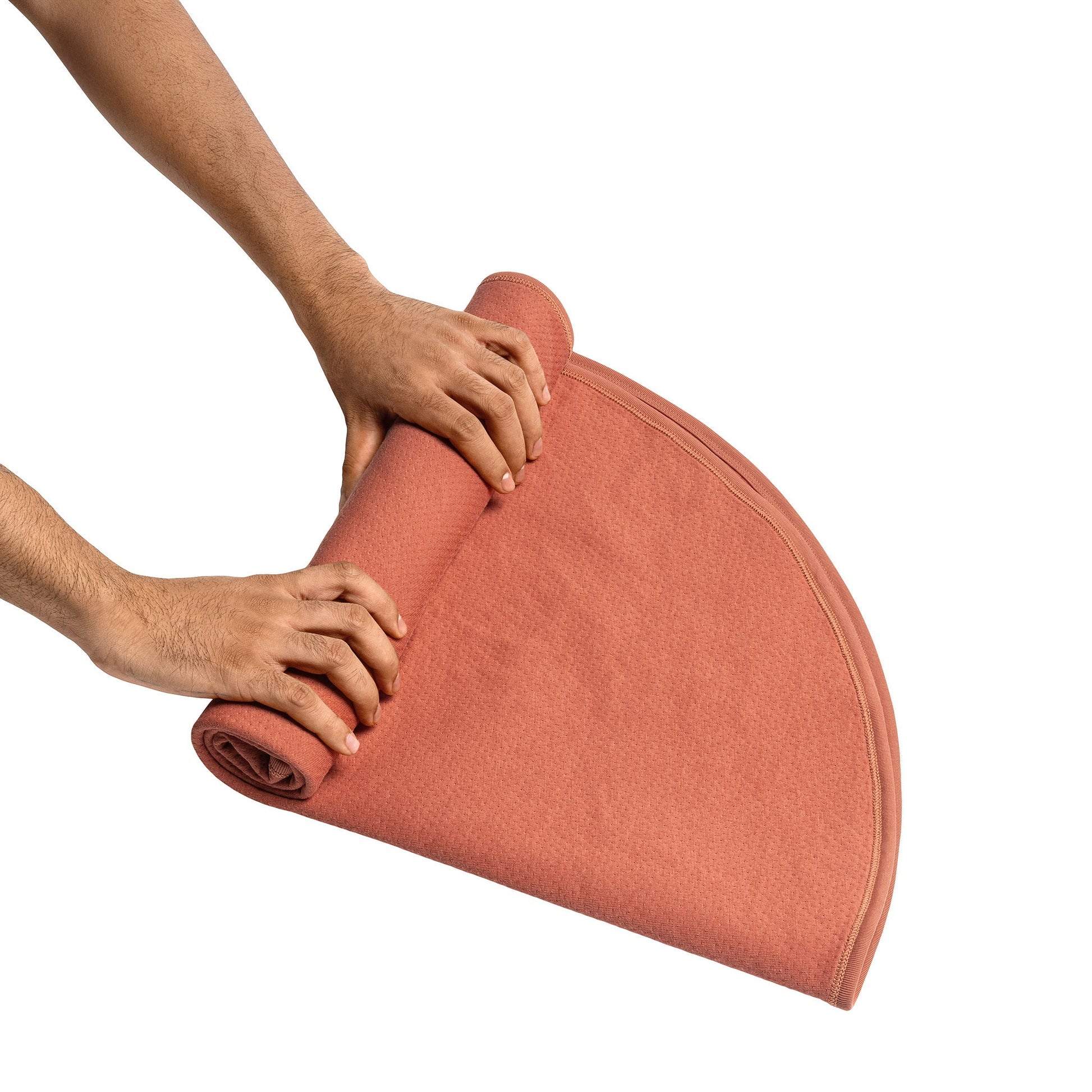 Copper waterproof sex blanket being rolled up by hands.