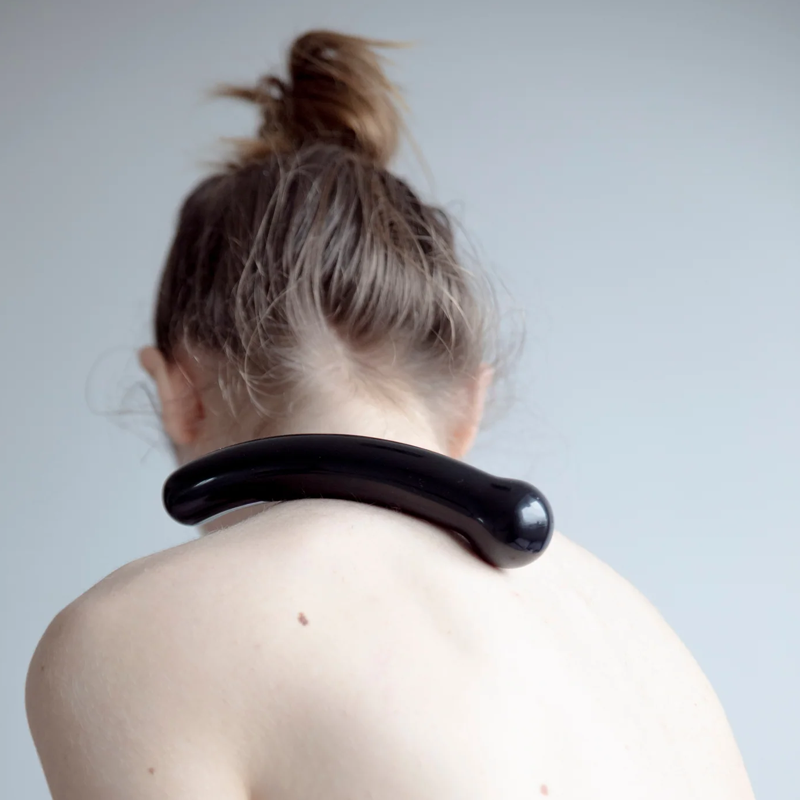 Curved black obsidian wand resting on a person's shoulders.