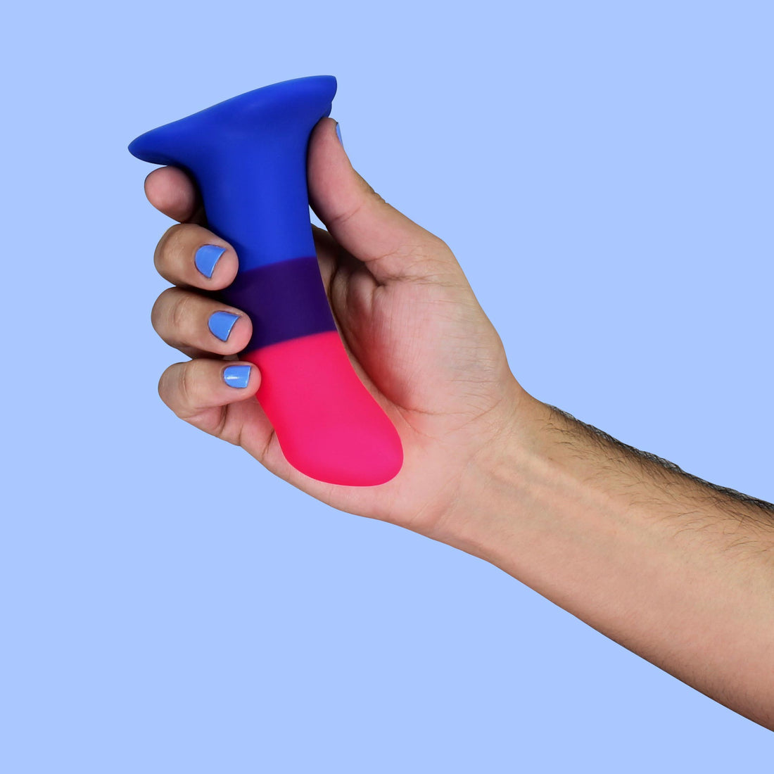 A hand holds a blue, purple, and pink dildo with a curved tip.