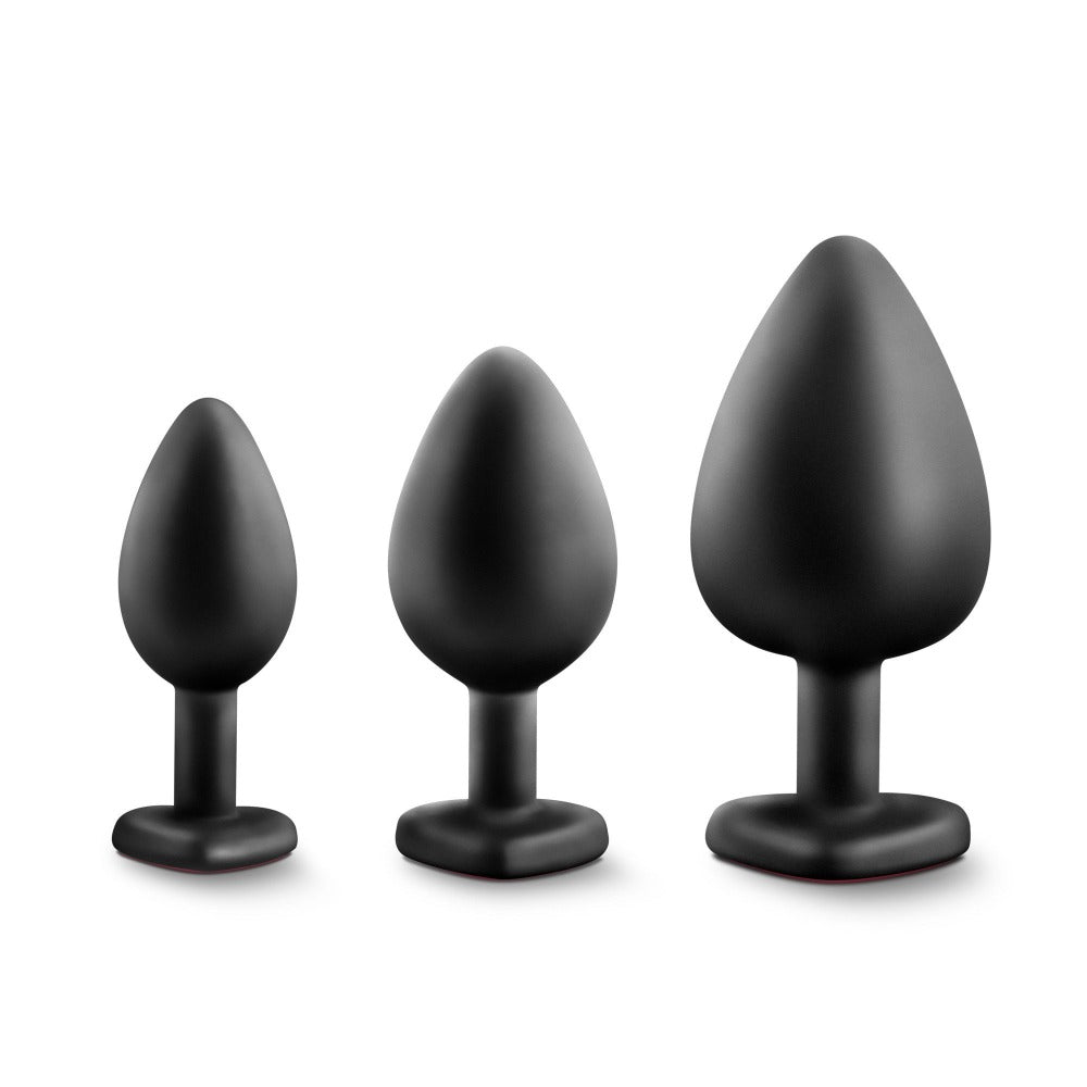 Three black silicone anal plugs of increasing size with red heart bases.