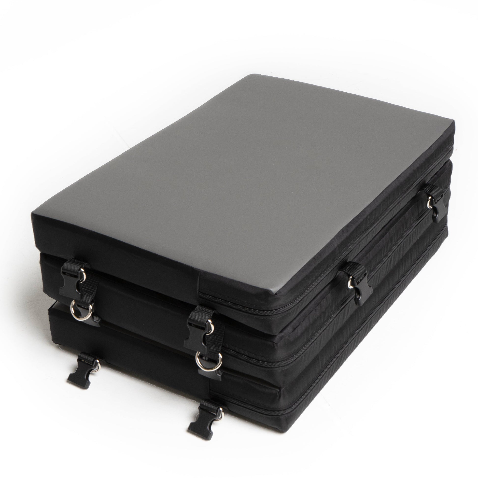 A grey faux leather portable bondage board folded with black straps and buckles.