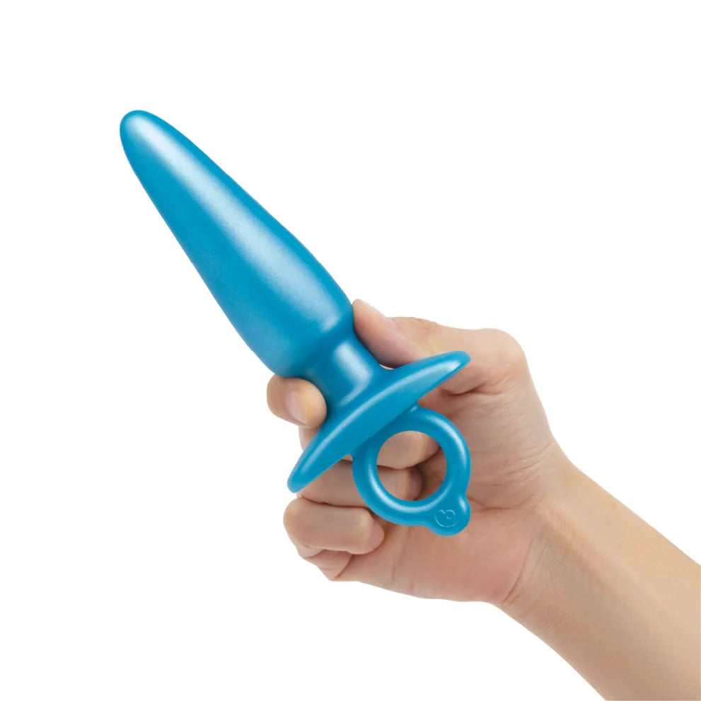 A hand holds a blue tapered silicone anal training plug with a ring.