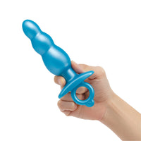 A blue beaded silicone anal plug with a finger ring is held in a hand.