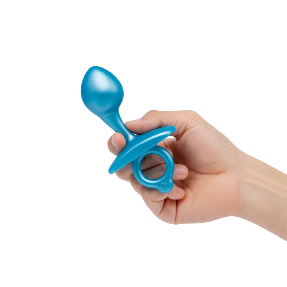 A hand holds a blue silicone prostate plug with a bulbous tip and a ring base.