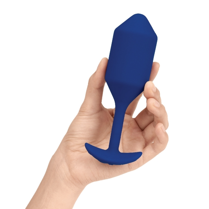A navy blue silicone vibrating snug plug held in a hand.