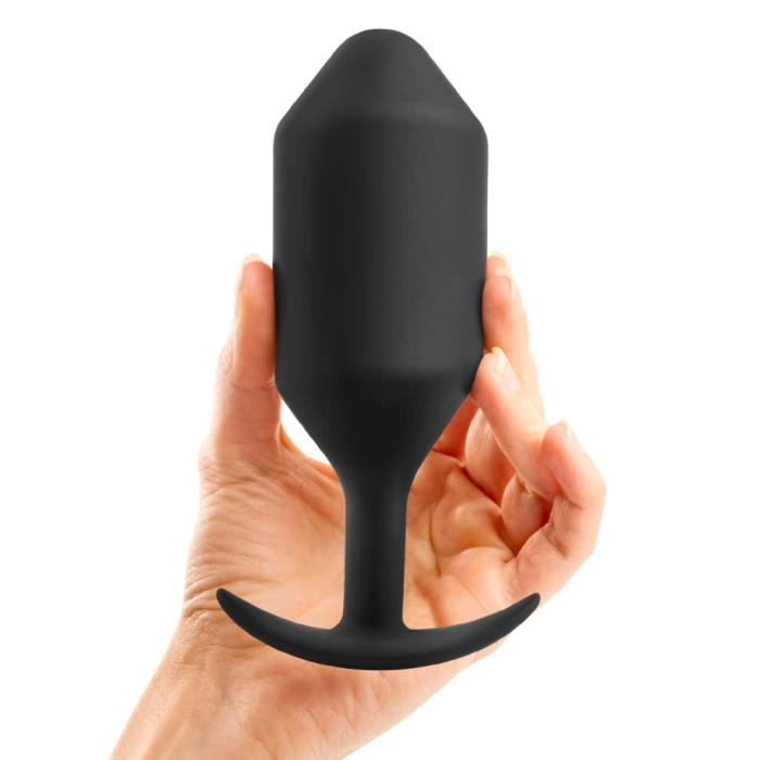 A black weighted silicone anal butt plug held in a hand.